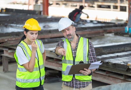 Senior engineer and female foreman worker team checking project at precast factory site, Engineer and builders in hardhats discussing on construction siteの写真素材