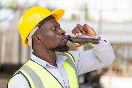 Engineer man drinking water at the precast factory site, Worker man drinking cola from a bottle on a siteの写真素材