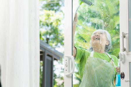Woman cleaning the house, Cheerful senior woman housekeeping, Professional female housekeeper with cleaning toolsの写真素材