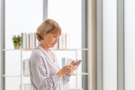 Caucasian woman using mobile smartphone in the living roomの写真素材