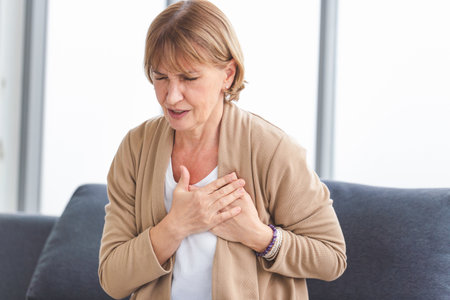Woman with pain on heart, Mature female presses hand to chest has heart attack suffers from unbearable painの写真素材