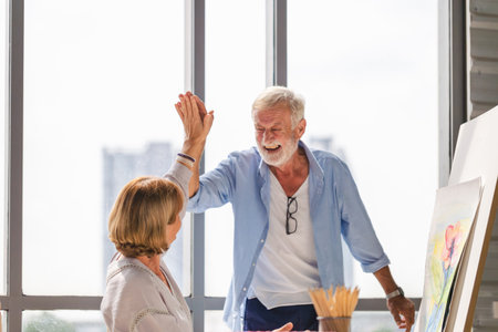 Cheerful senior couple spending time together in the living room, Happy senior couple painting on a...