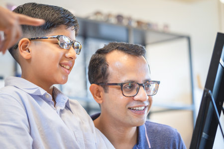 Indian father and son choosing eyeglasses in optics store