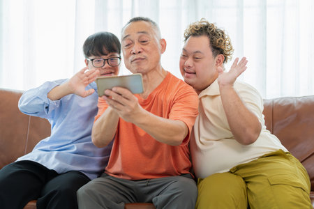 Grandfather and grandsons using smartphone doing a video call in living room
