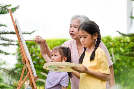 Grandmother drawing picture with grandchild in garden, Senior woman and kid girl play together in...