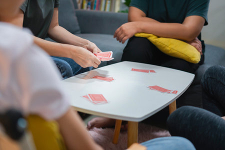 Asian family playing games together, Diverse people playing a card game in the living roomの写真素材