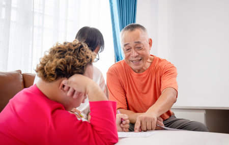 Senior man and grandchild practice math skill, interactive math game, Grandfather supervising grandchild sitting at sofa doing homeworkの写真素材
