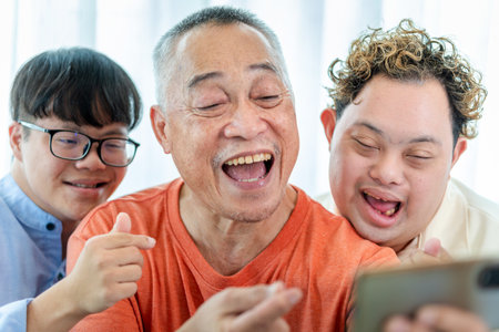 Senior man and grandchild using smartphone take selfie, Cheerful grandfather relaxing with grandchild and friends in living roomの写真素材
