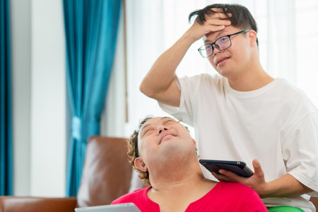 Cheerful Asian man and friend using tablet smartphone in living room, A group of friends relaxing and having fun in living roomの写真素材