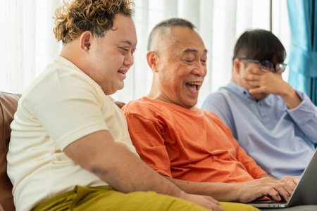 Senior asian man having a good time sitting on couch at home with adult son, Cheerful grandfather...