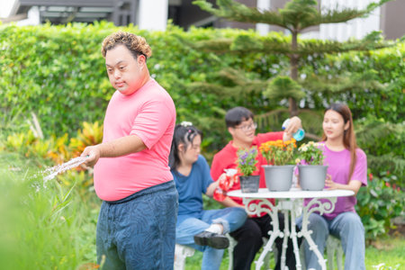 Group of friends take care plants in the front yard, Asian man watering the plants in the front yard gardenの写真素材