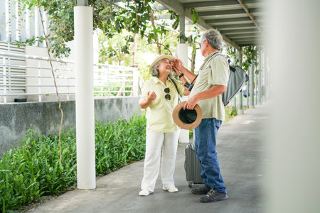 Happy Asian senior couple traveler with luggage walking in downtownの写真素材