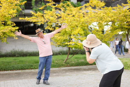 Happy Asian senior couple in park, Asian senior woman taking pictures using photo camera in parkの写真素材