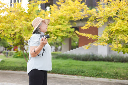 Senior Asian woman tourist with camera at park, Female photographer holding camera outdoorの写真素材