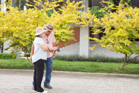 Happy Asian senior couple exciting and looking photo at camera in the park, Senior couple taking pictures using photo camera at parkの写真素材