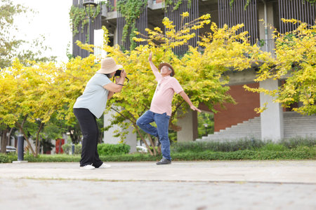 Happy senior couple in park, senior woman taking pictures using photo camera in parkの写真素材