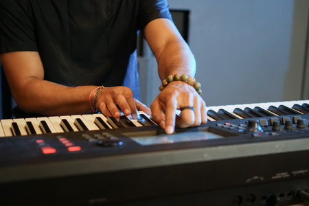 Musician playing music keyboard, Close up of Asian man hand in black shirt playing piano and practicing in home studioの写真素材