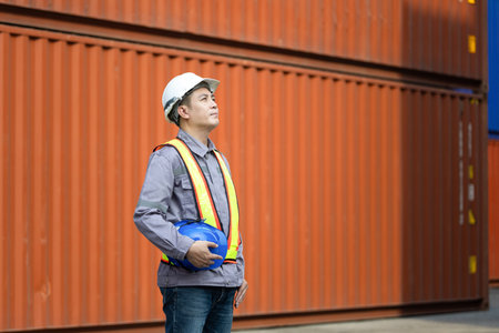 Engineer man in shipping container yard, Foreman dock worker in hard hat at industry containers...