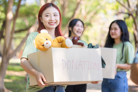 Smiling Woman Carrying a Donation Box with Teddy Bear, Helping Hands, Group of Volunteers Holding Donation Boxesの写真素材