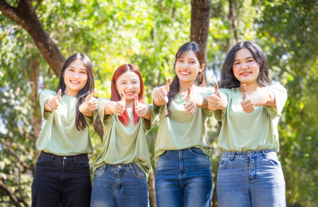 Group of Friends giving thumbs up outdoors, Happy young Asian female volunteer team in park for charity event with thumbs upの写真素材