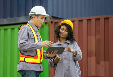 Female supervisor in safety gear and foreman worker in hardhat checking and control loading...