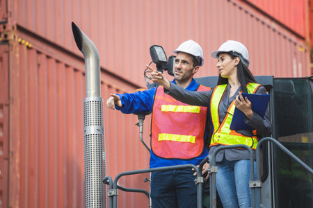 Supervisor in safety gear and engineer in hardhat checking and control loading containers box from shipping yard, Workers collaborating at shipping container cargoの写真素材