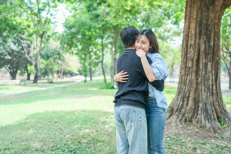 Young Couple Hugging Outdoors in Park on a Sunny Day, Joyful Hug Between Two People in a Green Park Settingの写真素材