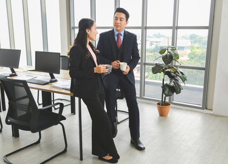 Business Colleagues Enjoying Coffee Break in Modern Office, Professional Team Chatting During Work Break, Friendly Conversation Between Coworkers in Office Settingの写真素材