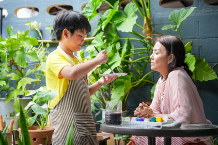 Mother and Son Painting Together in Garden, Kid Artist and Mom Resting and Drawing with Colorful Paints at Homeの写真素材