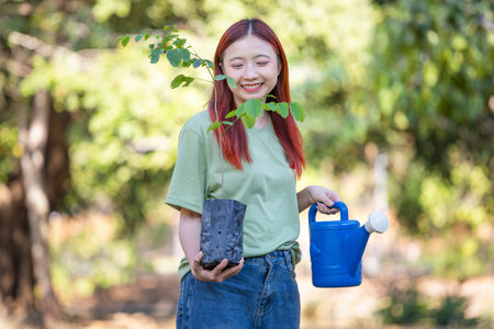 Young Female Volunteers Holding Plant and Watering Can, Ready for Tree Planting, Environmentalist Preparing to Plant Treeの写真素材
