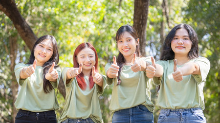 Smiling Young Asian Women Giving Thumbs Up in Nature, Group of Happy Female Volunteers Friends Showing Approval Outdoors, Positive Youth Giving Thumbs Up, Nature Backgroundの写真素材