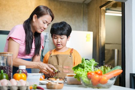 Mother and Son Bonding While Preparing Healthy Meal in Kitchen, Happy Asian Family Cooking Fresh Vegetables Together at Home, Cute Boy Learning to Cook with Mom, Healthy Lifestyle Conceptsの写真素材