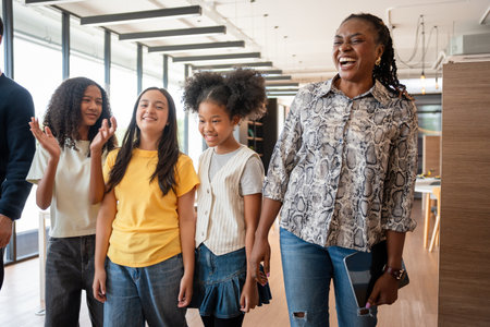 Adult Professionals Guiding and Interacting with Young People in a Contemporary Setting, Diverse Group of Mentors and Students Walking and Talking in Modern Spaceの写真素材