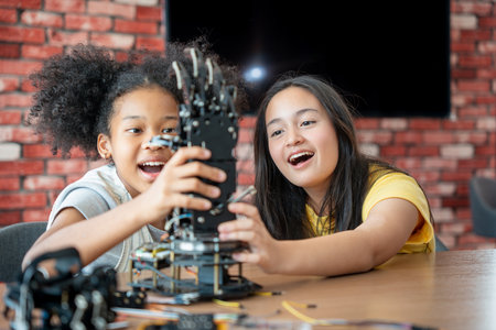 Children Learning Robotics, Young Girls Engaged in Robotics and STEM Learning, Diverse Kids Building a Robot Arm in a Science Workshop, Two Girls Exploring Technology and Innovationの写真素材