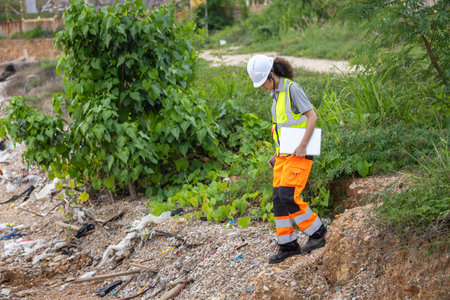Female Engineer in Safety Gear Inspecting Coastal Shoreline with Laptop, Environmental Inspector...