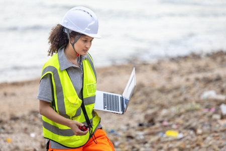 Environmental Engineer Testing Water Quality at Drainage Site, Field Scientists with Walkie Talkie and Laptop Conducting Water Pollution Analysis Outdoorsの写真素材