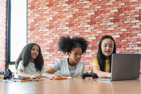 Diverse Young Girls Working Together on Programming and STEM Project, Multicultural Students Learning Coding and Robotics on Laptop in Class, Group of Children Collaborating on a School Projectの写真素材
