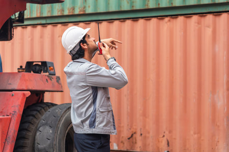 Technician checking forklift equipment during cargo operations, Logistics worker performing safety inspection on heavy-duty vehicle, Industrial worker inspecting heavy machinery at container yardの写真素材