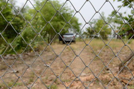 Wire mesh fence with blur farm background in the countryside of Thailandの写真素材