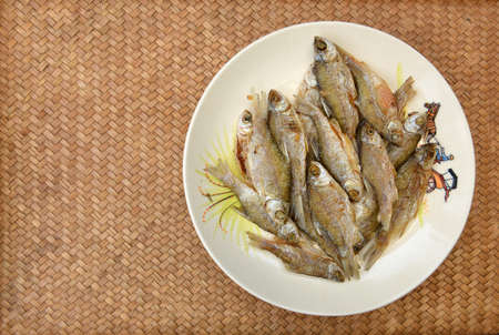 Fried fish lays on a white plate. Thai food in countryside.の写真素材