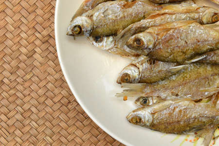 Fried fish lays on a white plate. Thai food in countryside.の写真素材