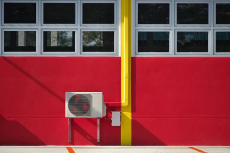 Air conditioner compressor installation on red wall, outdoorsの写真素材