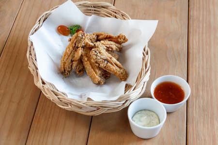 Fresh fried chicken on a wicker basket  set on a wood tableの写真素材
