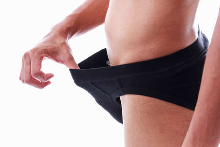 Concept photo of male sexuality and problems. Man pulling his black underwear.の写真素材