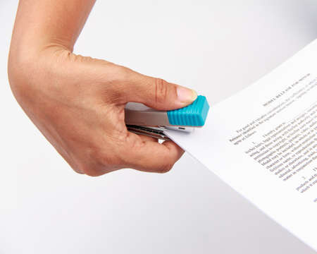 Close-up of woman's hand stapling paper on white background