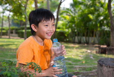 asian boy drink water thirsty tired park nature outdoors happyの写真素材