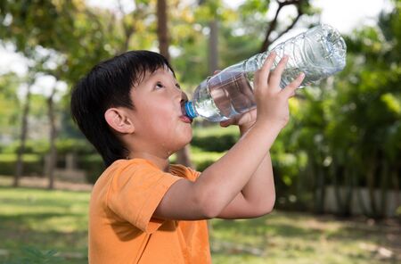 asian boy drink water thirsty tired park nature healthy outdoorの写真素材