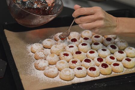 Woman filling jam into Christmas cookiesの写真素材