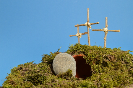 resurrection garden as easter decoration with a stone near the empty tomb and three crosses on a hill aboveの写真素材