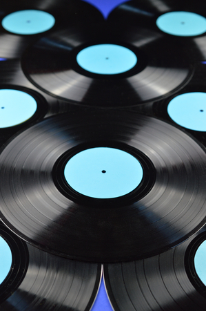 pile of old black vinyl records with blank labels cyan on blue background